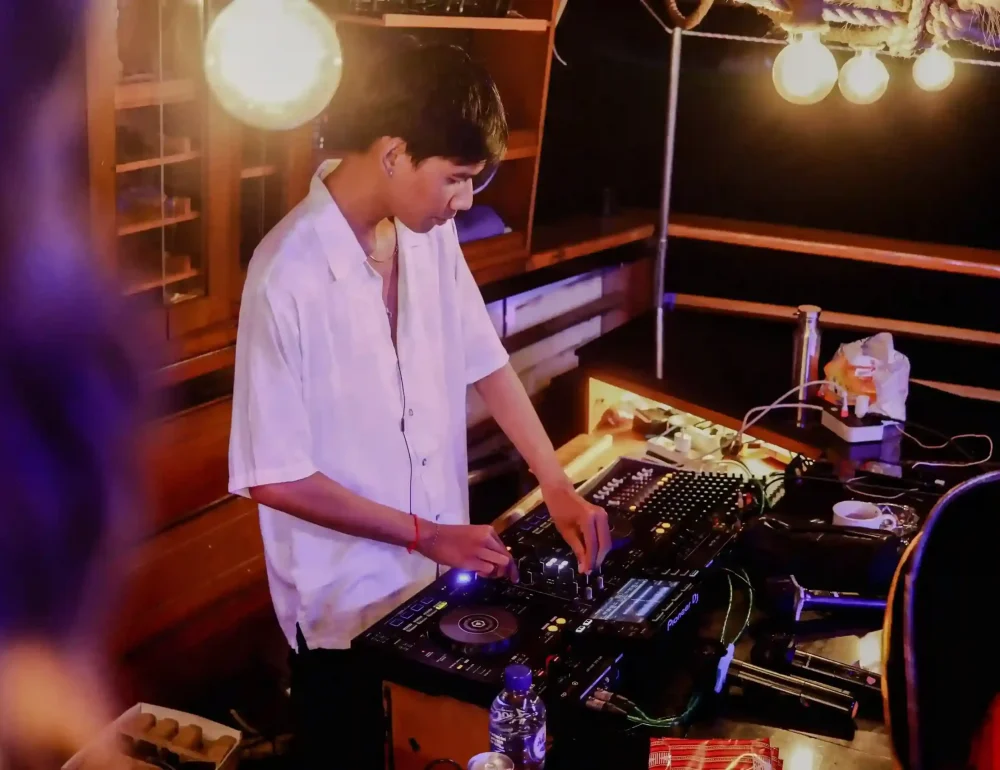 A DJ playing on the deck of an evening boat party